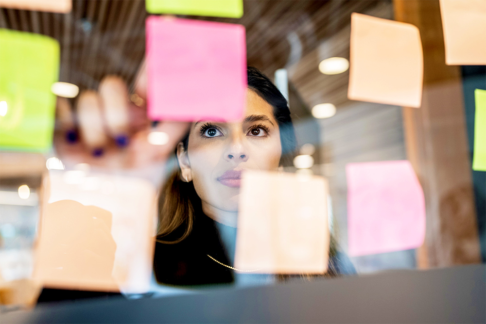 Woman planning a project with sticky notes on a glass wall